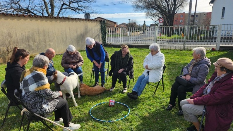 Un groupe de personnes âgées est réunie autour de deux chiens