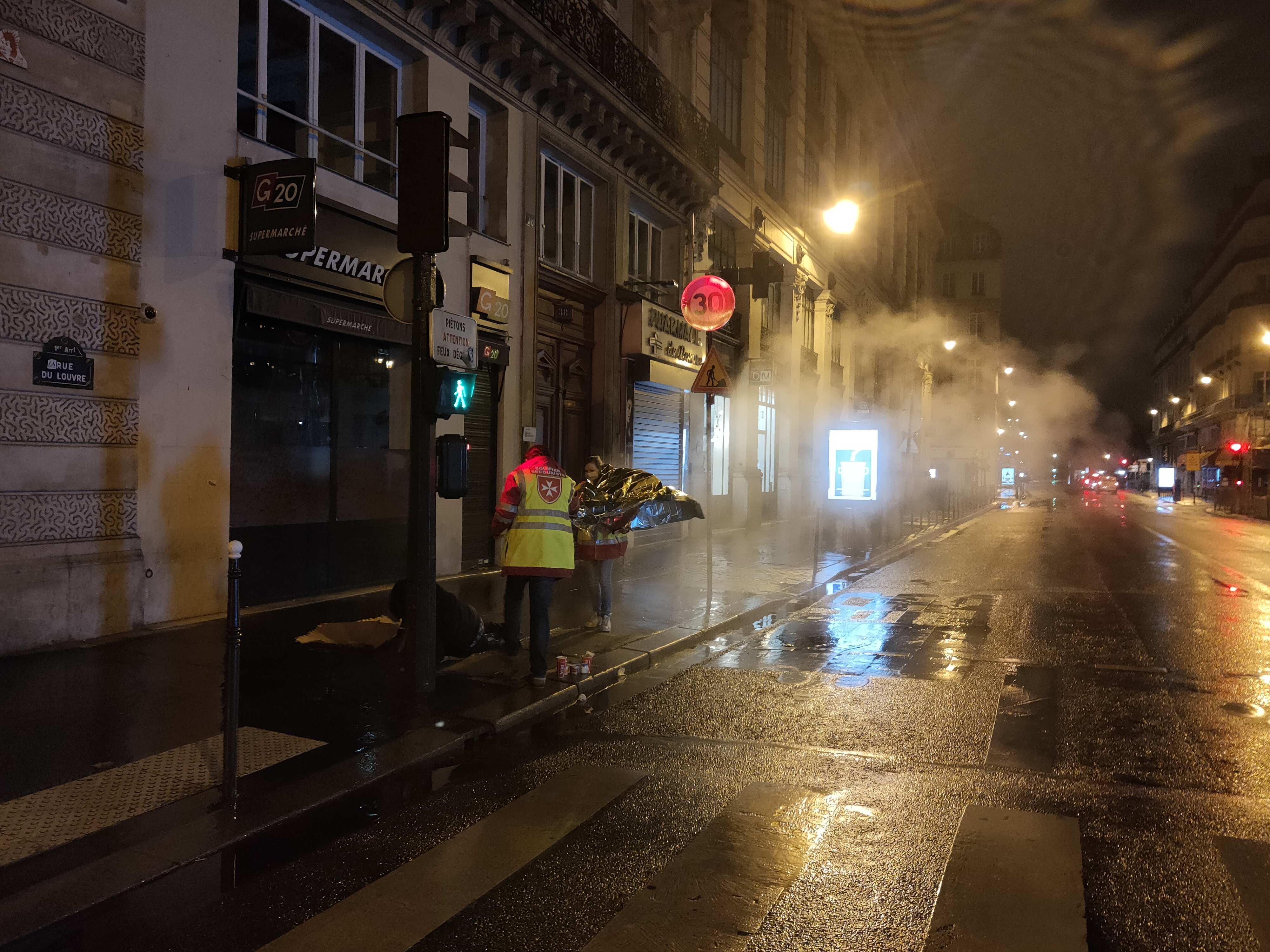 Légende : Cédric et Constance recouvrent l’homme rencontré rue du Louvre avec une couverture de survie donnée par un agent de la RATP. Crédit photo : Carenews.