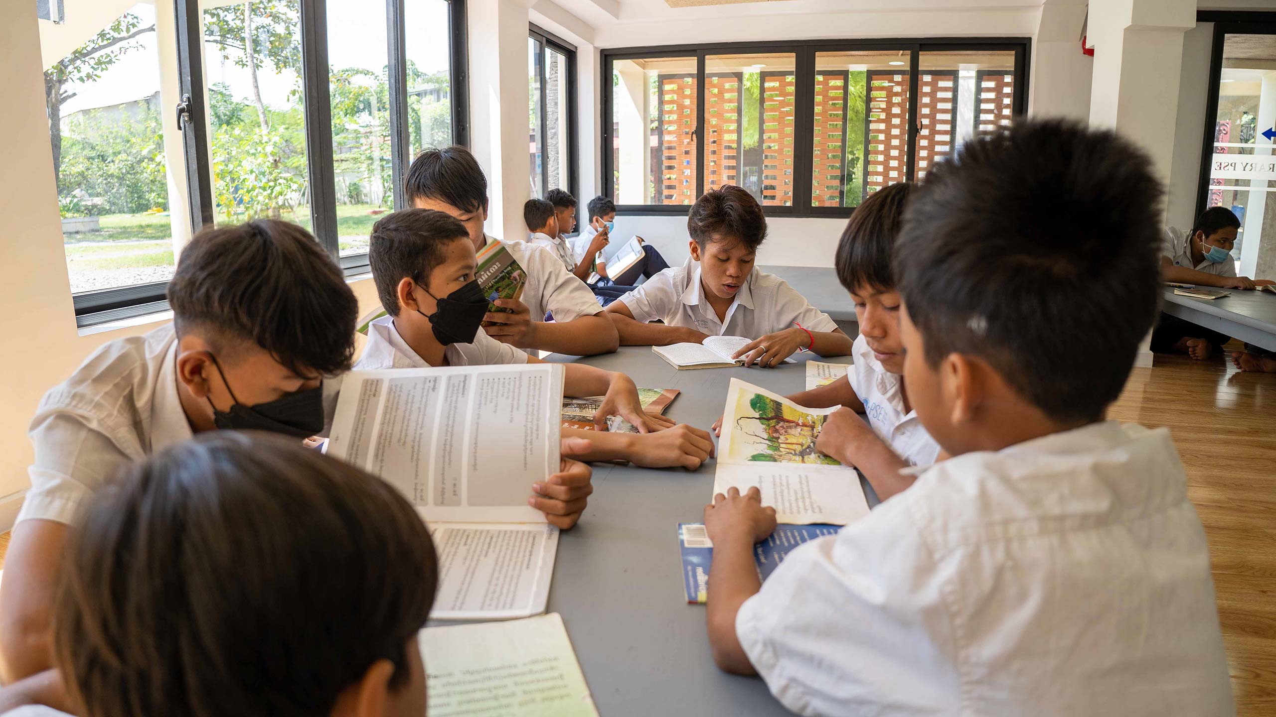 Des enfants assis lisent des livres dans la bibliothèque rénovée de l'école Pour un Sourire d'Enfant