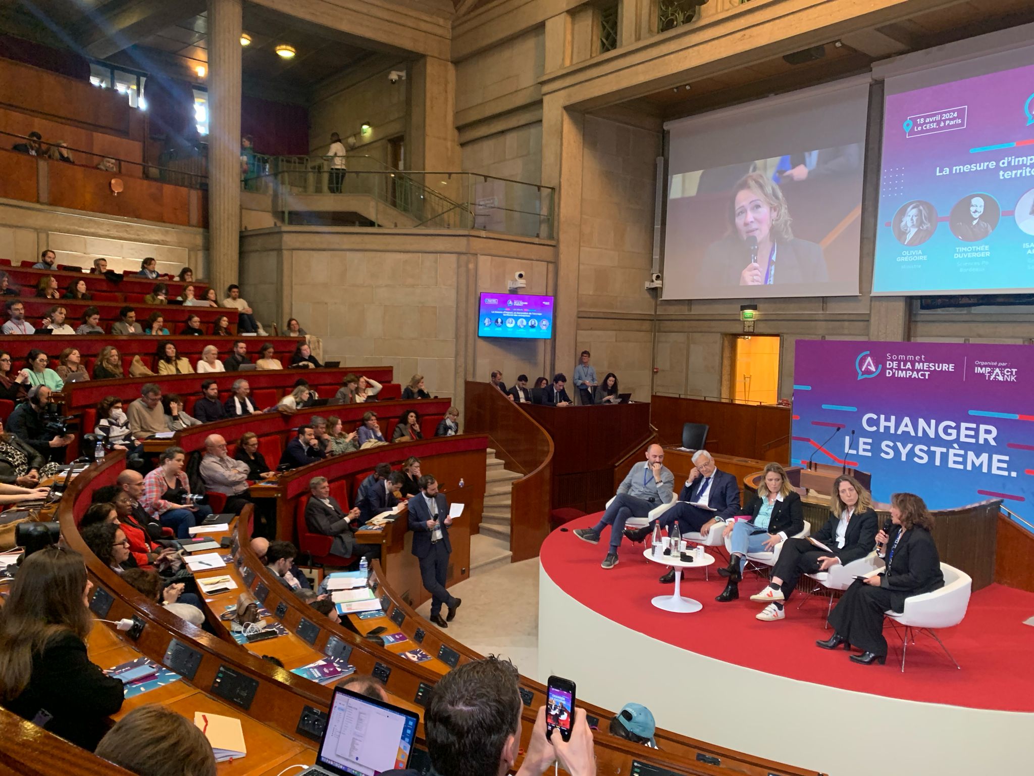 Photographie de l'hémicycle pendant la table-ronde avec les 5 intervenants sur scène. 