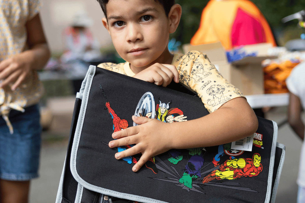 Garçon tenant fièrement son nouveau cartable