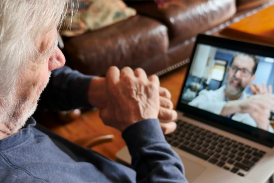 Une personne âgée se touche le poignet lors d'une téléconsultation avec un médecin - © Getty Images