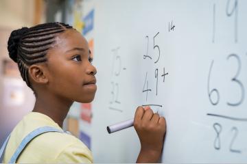 jeune élève qui résout une addition au tableau