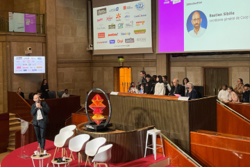 Les élèves de CM2 de l'école Belleville, à Paris (20e arrondissement), au Conseil économique, social et environnemental, lors de l'événement de clôture de l'Année internationale des coopératives, derrière Bastien Sibille, secrétaire général de Coop FR, et la flamme coopérative. Crédit : Carenews. 